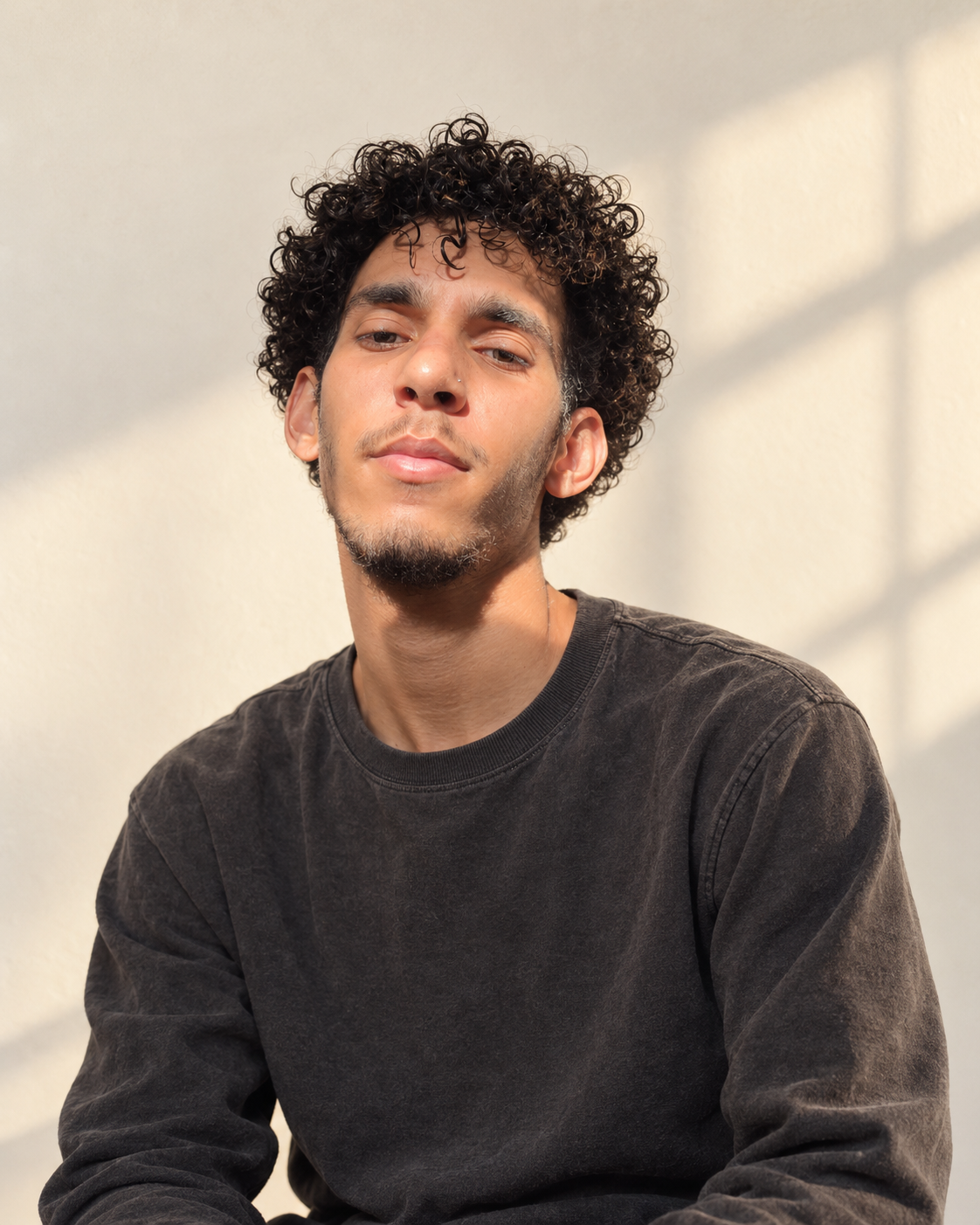 Portrait of Christopher wearing a charcoal shirt against a warm cream backdrop